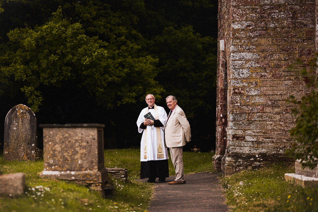 vicar and verger outside of wedding chapel 