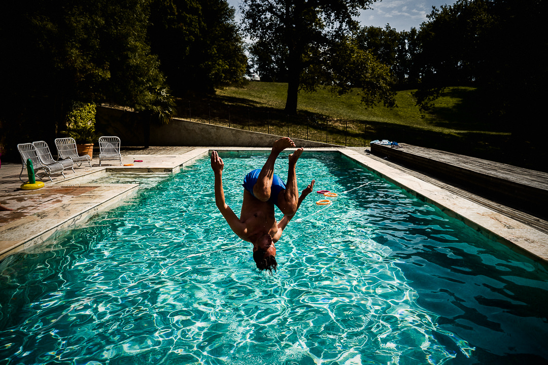 Wedding guest summersaulting in to the pool at Chateau Lartigolle