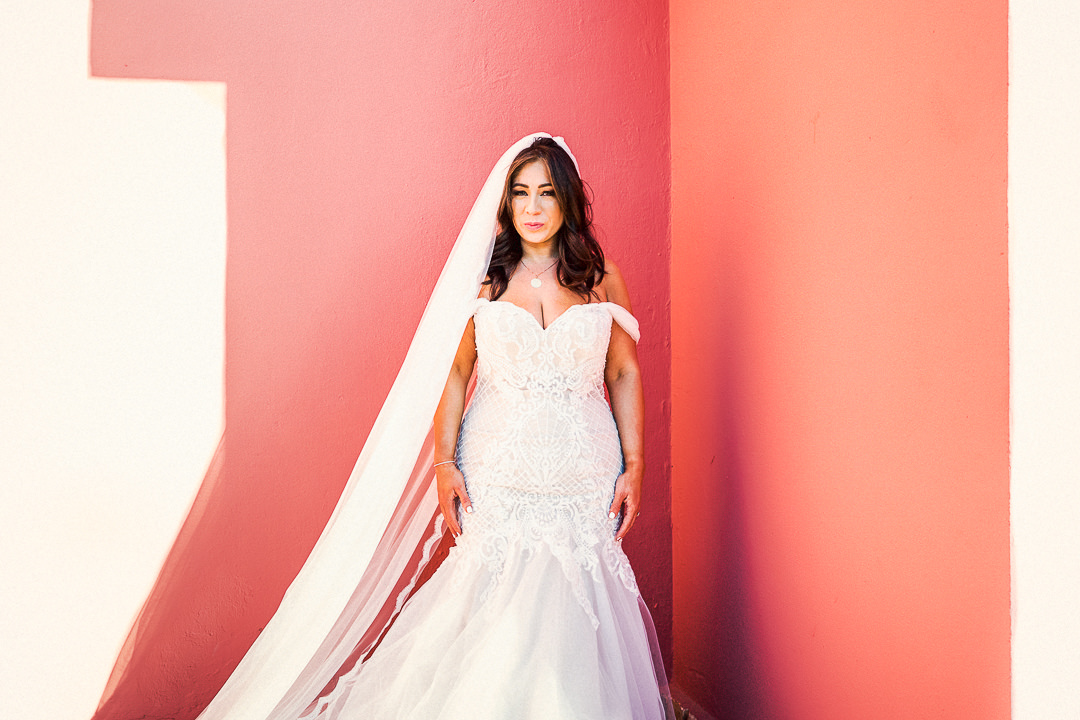 a bride stood against a pink wall in ibiza