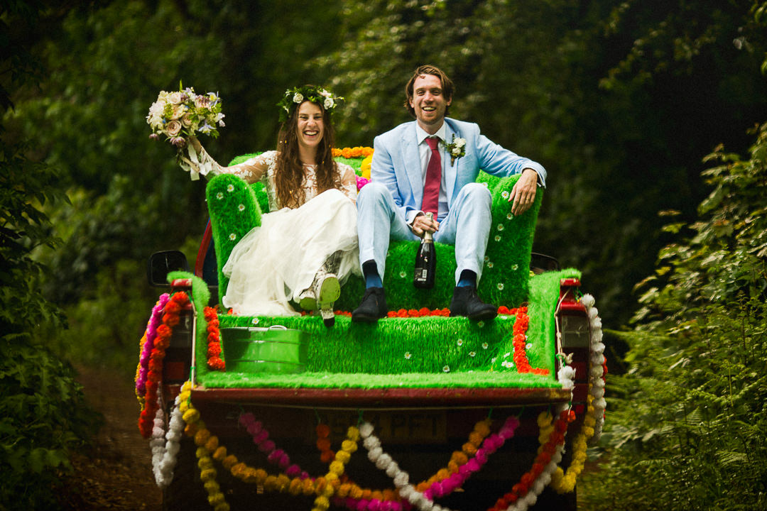 a wedding couple sit on a sofa attached to a pick up truck on their wedding day