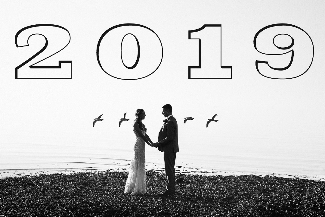 a couple face each other hand in hand for an alternative wedding photograph by the sea in whitstable. 4 gulls pass and frame them against the white sky 