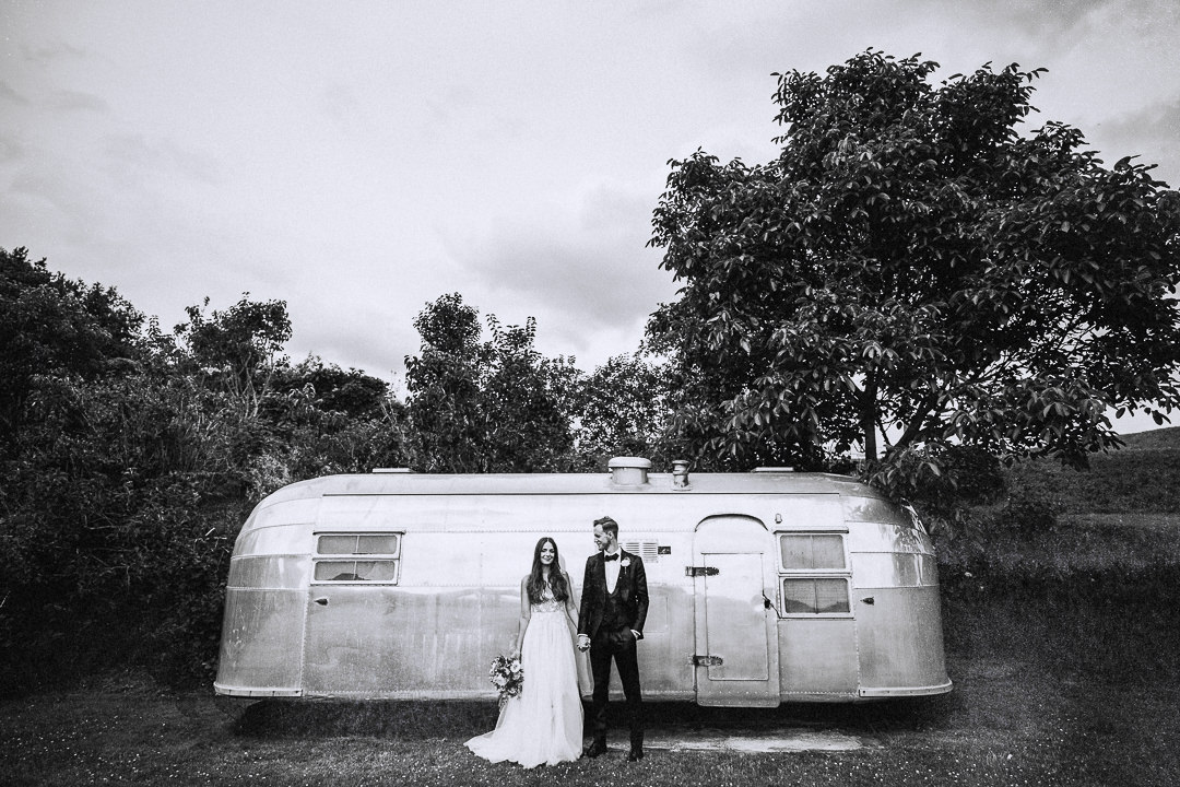 a couple posing in front of an airstream caravan