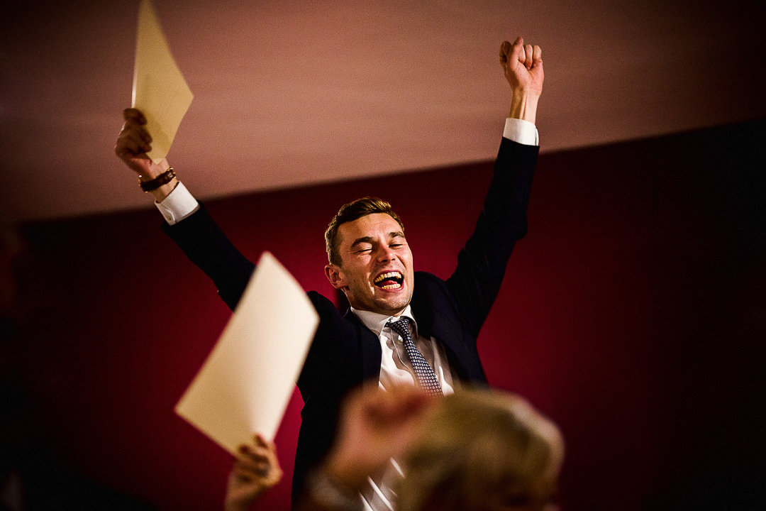 a wedding guest with his hands in the air singing a song during the wedding speeches 
