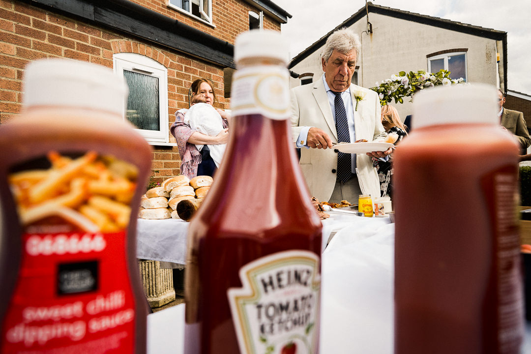 a wedding guest at the hog roast buffet table with condiments out of focus in the foreground 