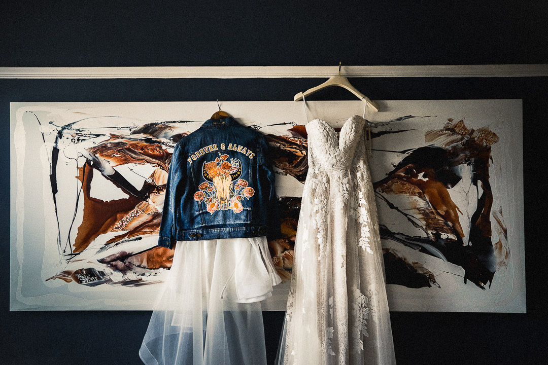 2 bridal dresses and a bespoke denim jacket hanging at the brides home pre wedding ceremony in London