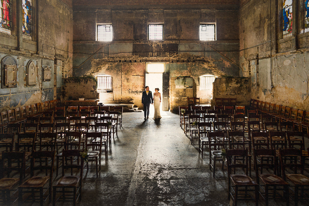 a wedding couple walk hand in hand through the asylum chapel in Peckham, London