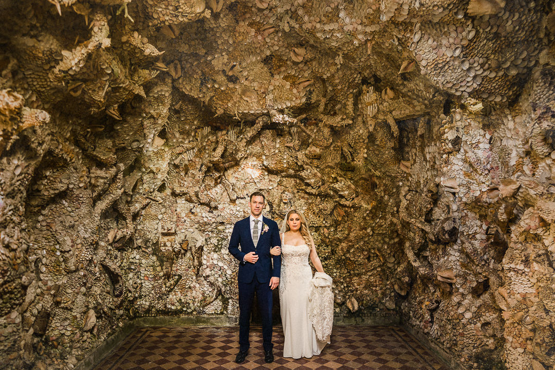 a wedding couple stand for a portrait in a shell grotto at st Giles house in Dorset