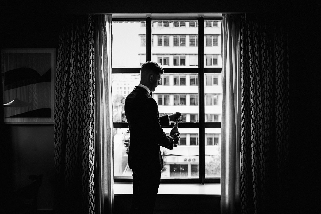 a wedding groom opens a bottle of Prosecco at the Hoxton hotel