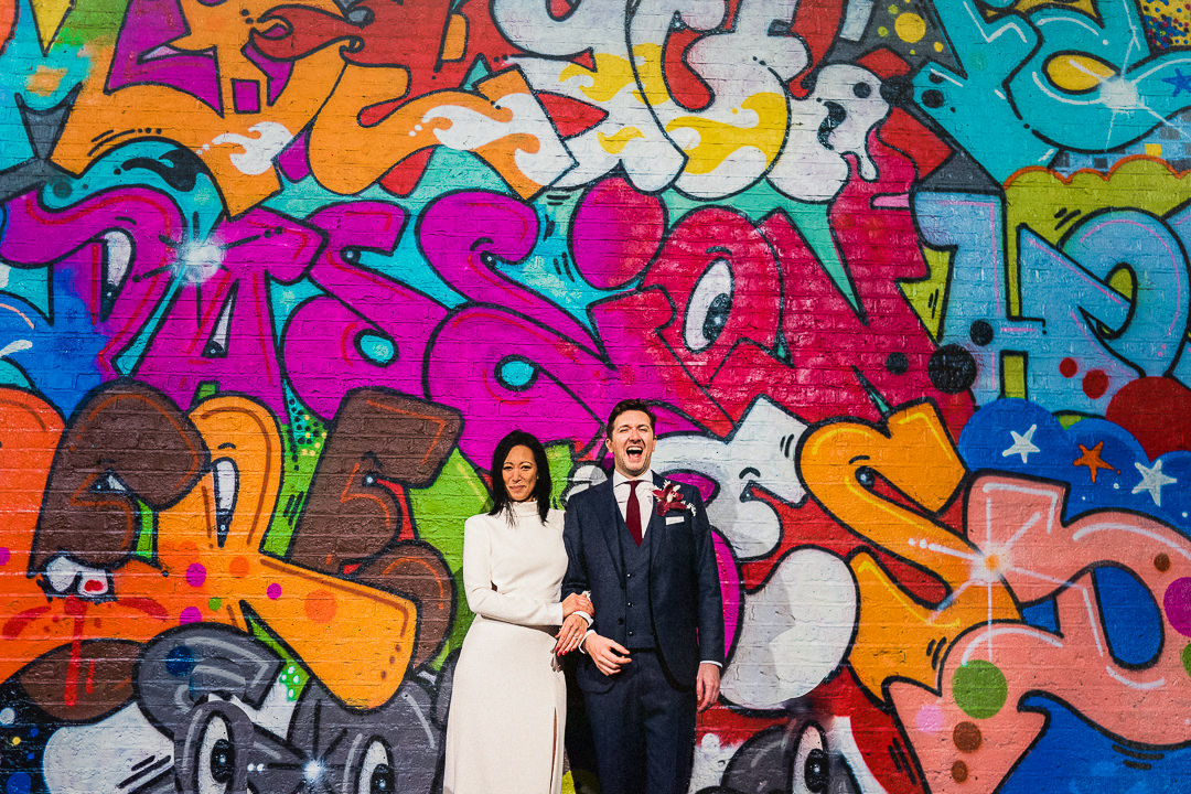 a wedding couple stand against a backdrop of an East London graffiti wall