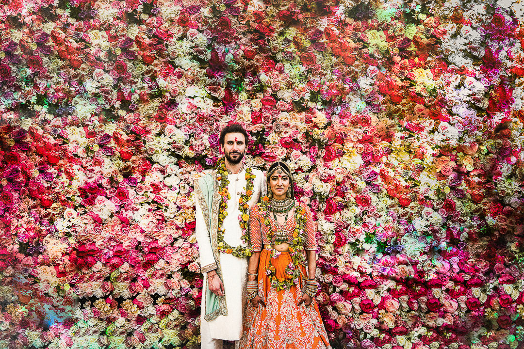 A couple pose for a portrait against crazy background during their Indian wedding celebrations