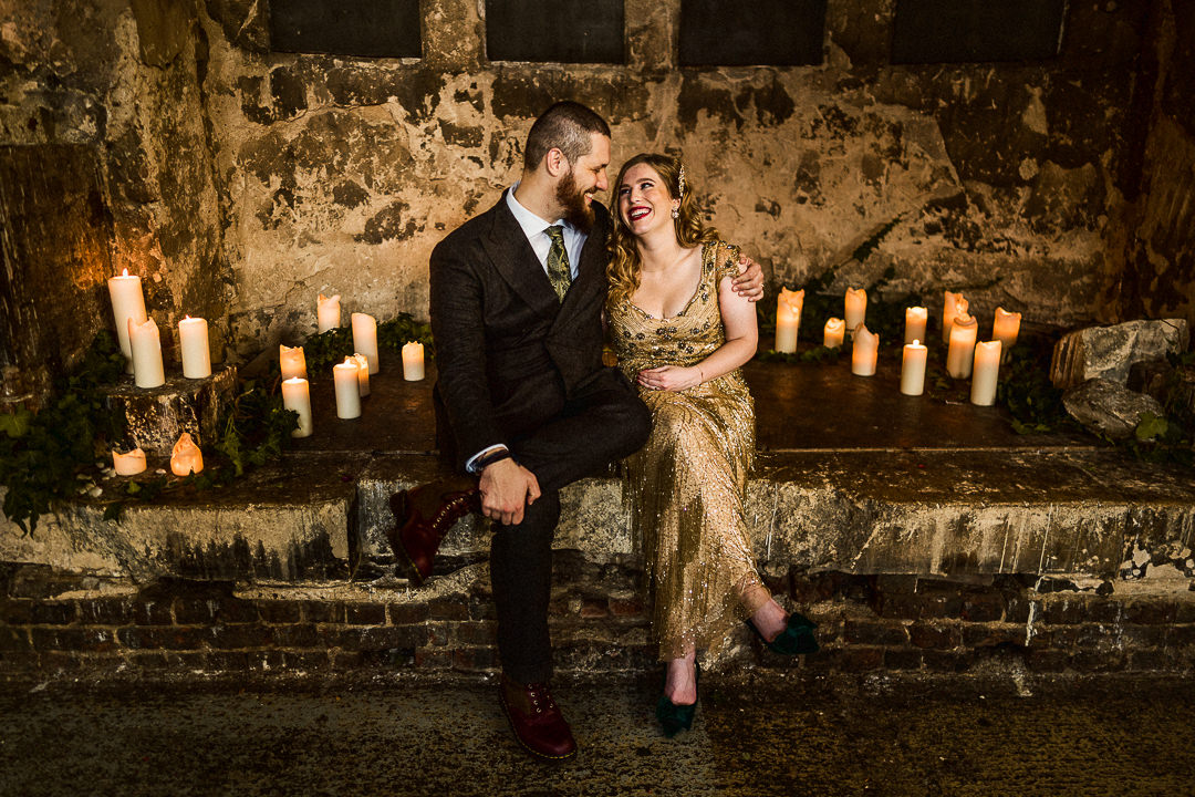 a smiley happy couple sit on the candlelit stage at the asylum chapel wedding venue in London